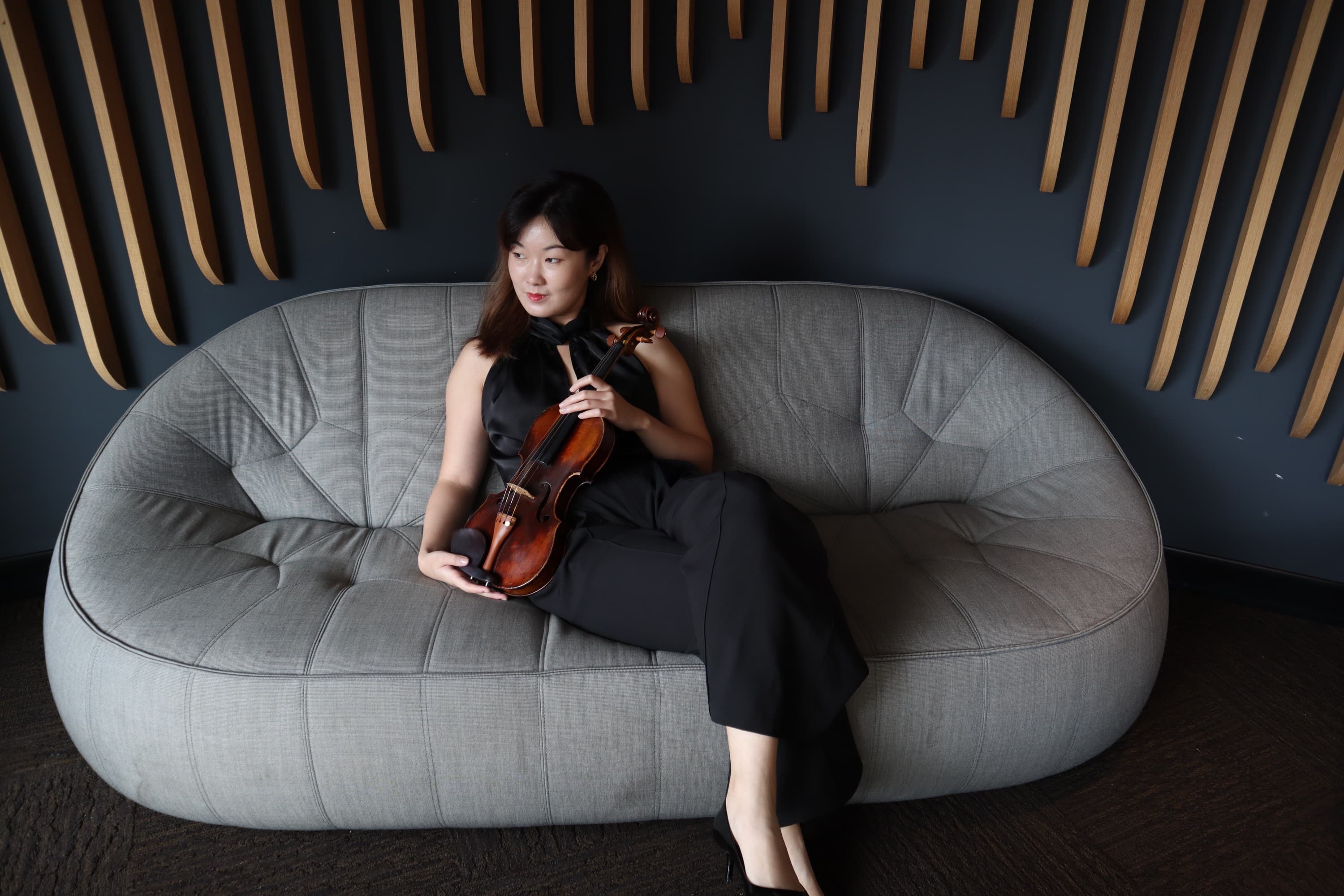 Bin Gui seated with her violin